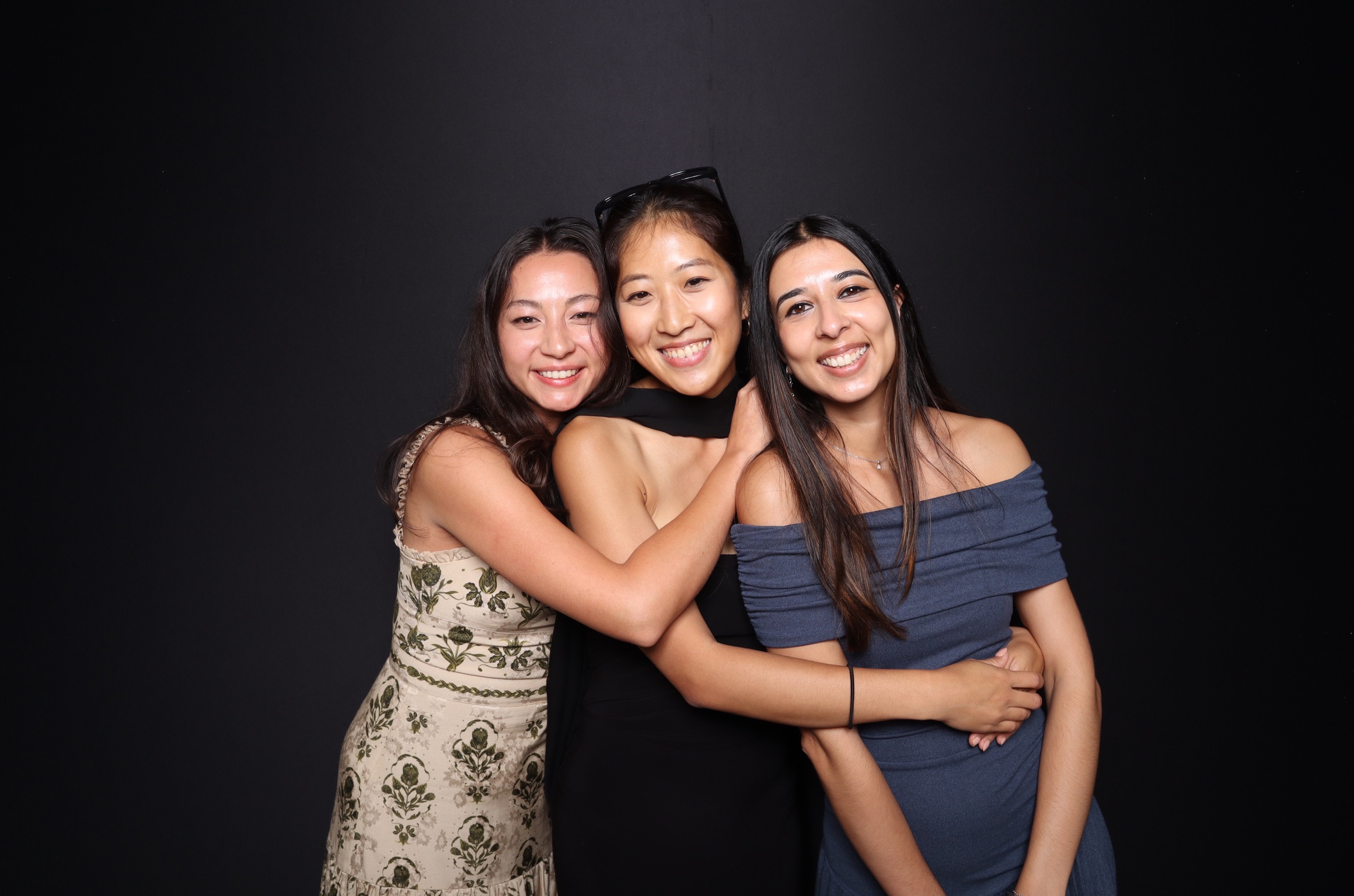 Three guests smiling in front of the black photobooth backdrop.