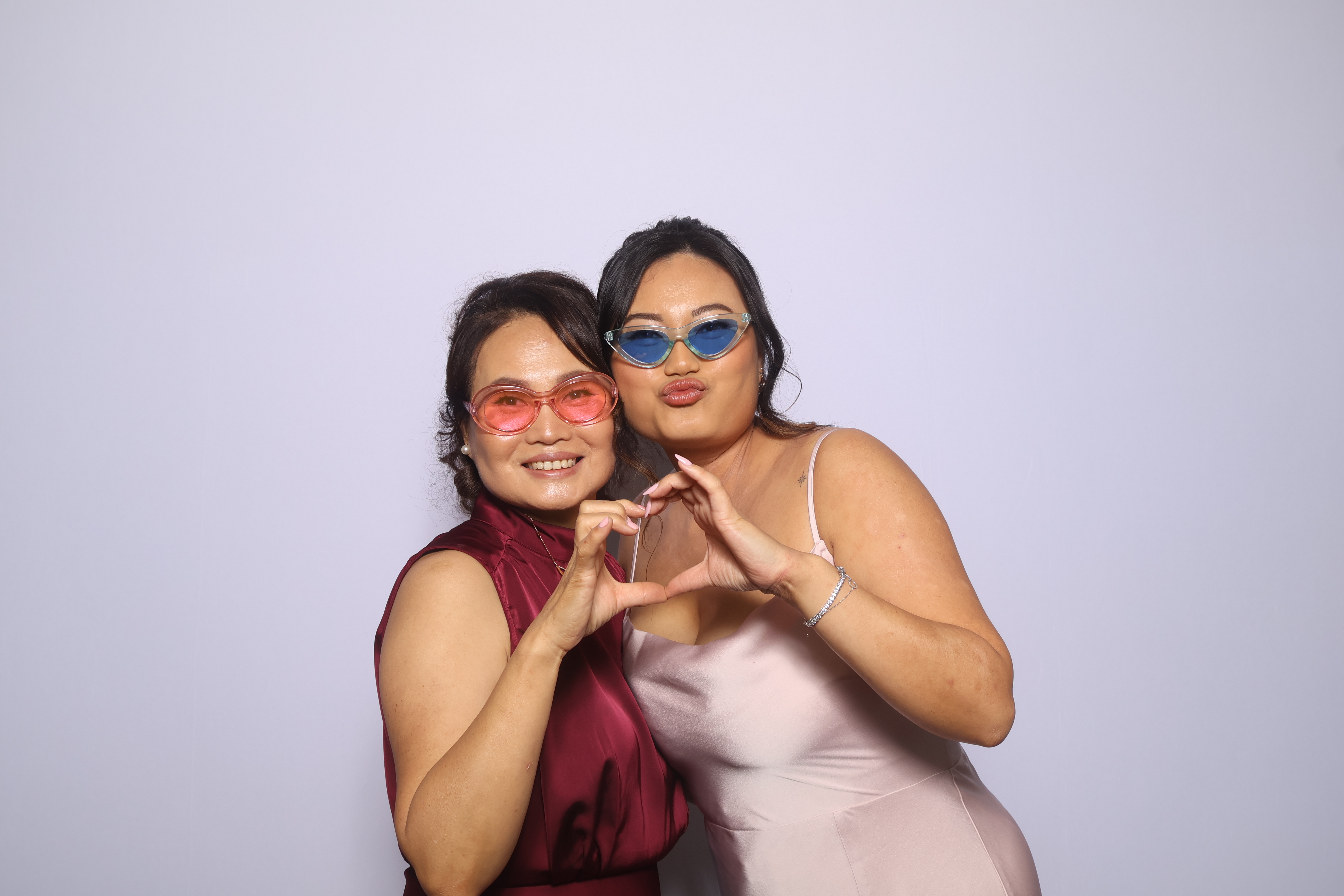 Two guests posing in front of the white photobooth backdrop.
