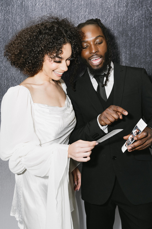 Bride and groom smiling while looking at photobooth prints